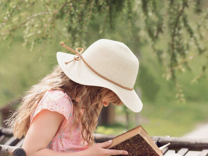 Bambina legge un libro in un parco con aria serena