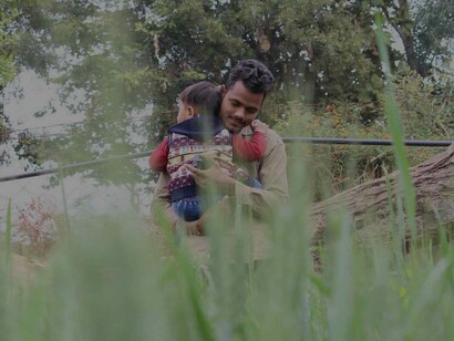 A man in the park is hugging his child dearly as a way to calm the infant which shows signs of caring parenting