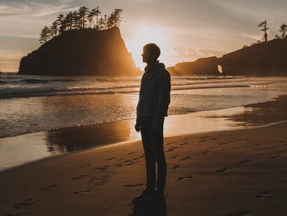 In the quiet of the evening, as the sky fades to twilight, the lone figure on the beach contemplates the layers of his identity, unveiled in the absence of others