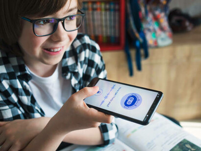 A smiling boy interacts with an AI chatbot on a mobile application, exploring the capabilities of artificial intelligence and virtual assistance through futuristic technology