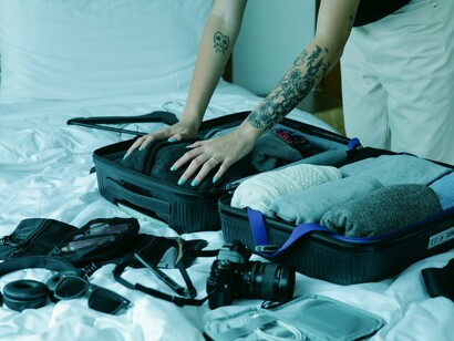 Mulher arruma mala para viagem. Estar de fato na casa de uma pessoa local, compartilhando da sua intimidade, é uma experiência incrível. A forma mais autêntica de estar inserido nos costumes e modo de vida de cada região