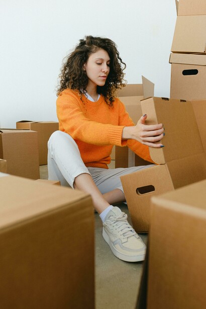 A young woman organizes cardboard boxes during a move, marking a fresh start