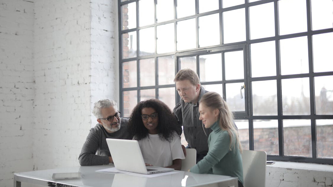 Sports managers collaborate around a computer, strategizing the future of sport management in an ever-evolving industry