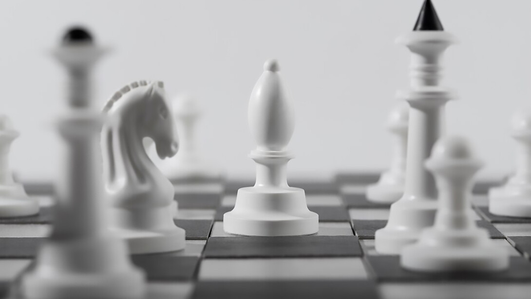 A monochrome set of white chess pieces arranged on a chessboard