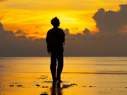 Silhouette of a traveler walking on the beach at sunset