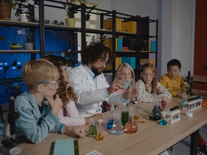 Em uma aula de laboratório de ciências, alunos do ensino fundamental 1 olham curiosos uma reação química