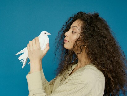 A woman gazing thoughtfully at a white dove, symbolising the mindful awareness that allows emotions to be felt without taking control