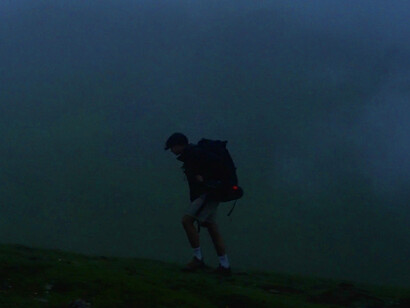 As he ascends the mist-covered trail, the solitary figure reflects the journey of self-discovery, illustrating the tension between survival and maintaining one’s identity