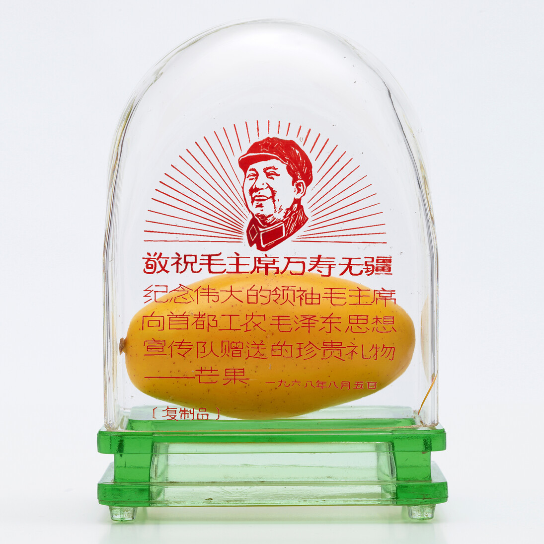 Mango vitrine with likeness of Mao and standard inscription: “Respectfully wishing Chairman Mao eternal life. To commemorate the precious gift presented by Great Leader Chairman Mao to the Capital Worker-Peasant Mao Zedong Thought Propaganda Teams – Mango. 5 August 1968,” c.1968-69. Glass, red enamel 20.3 x 14 x 9 cm. Papier-mâché mango, 13 cm. 