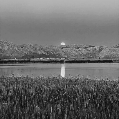 Luna nascosta dietro i monti riflette la propria luce nel lago 