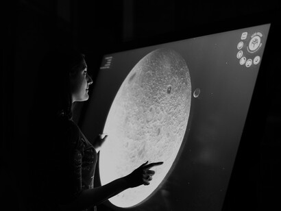 Mujer interactúa con una pantalla tactil en una exposición