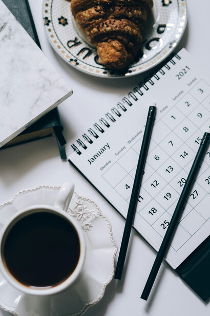 A cup of black coffee sits beside a calendar