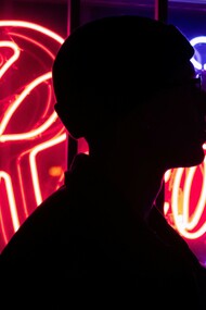 Silhouette of a person standing by neon lights at night