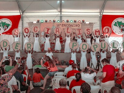 Participantes de um evento do MST exibem cartazes formando as palavras "Socialismo" e "Poder Popular". A organização coletiva é apontada no artigo como um elemento central para a reconstrução das esquerdas