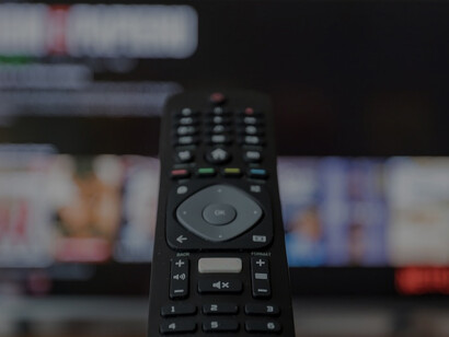 An individual gripping a black remote control while enjoying streaming platforms