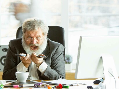 Uomo che urla a due telefoni: "Anche la comunicazione potrebbe ben risentirne, riducendo la quantità di messaggi per aumentare la qualità della comunicazione"