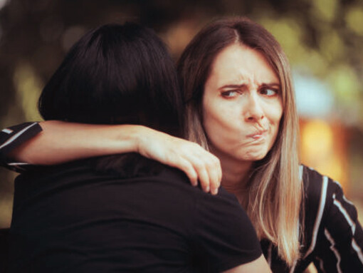 A woman embraces a fake friend who secretly mocks her behind her back
