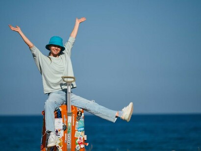 A woman standing on a beach with a suitcase, living the nomadic life while working from anywhere in the world