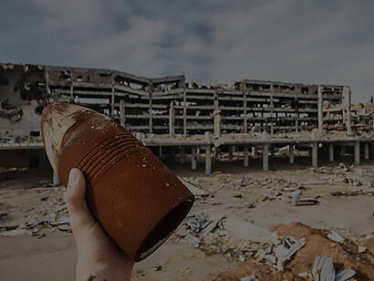 Discover the harrowing reality of the Ukraine conflict with an image of a person holding an unexploded 120 mm shell amidst airport ruins, highlighting the ongoing devastation