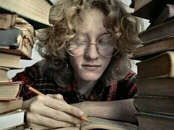 Homem escreve em meio à pilha de livros. A responsabilidade da IA pelos milhões de brasileiros com dificuldades graves em leitura e escrita é inexistente. Dados do Inaf (Indicador de Alfabetismo Funcional) evidenciam que, entre 2001 e 2024, o analfabetismo no Brasil caiu de 12% para algo entre 4% e 7%. Um progresso? Talvez. Mas o mesmo estudo indica que a parcela da população em nível proficiente — capaz de interpretar textos complexos e fazer inferências — permanece estagnada em apenas 12% há mais de vinte anos


