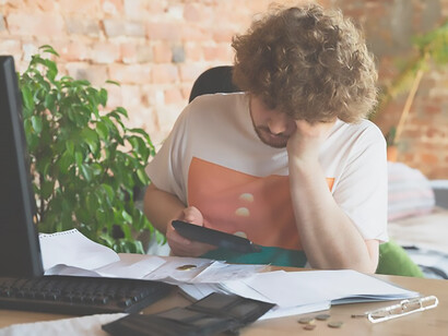 Poignant depiction of a despondent man immersed in financial and economic charts during daylight hours, conveying feelings of distress and disillusionment
