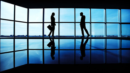 Shadowed figures of business people in a sleek, modern office setting