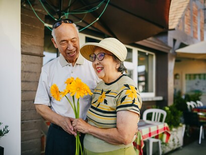 An older man giving his wife some yellow flowers 
