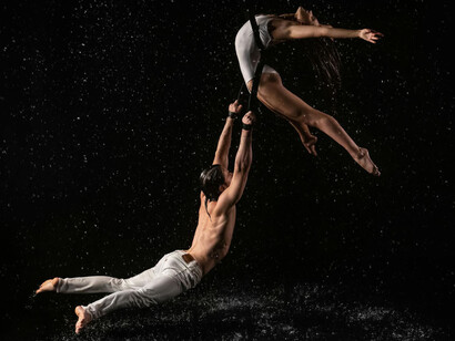 Hombre y mujer practicando acrobacia bajo la lluvia