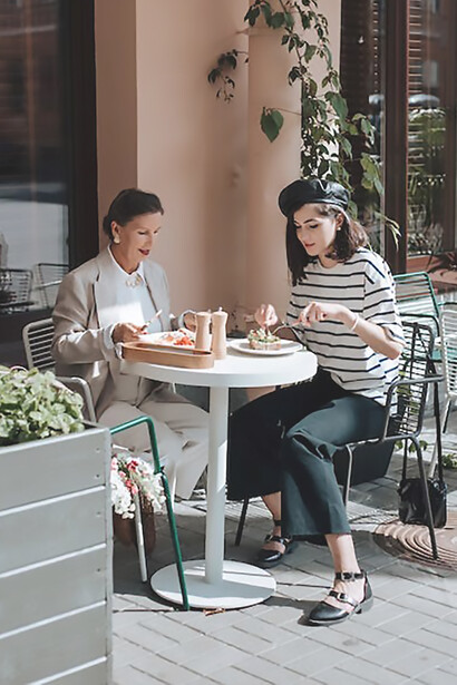 Two women are eating and drinking in a nice cafe during the day