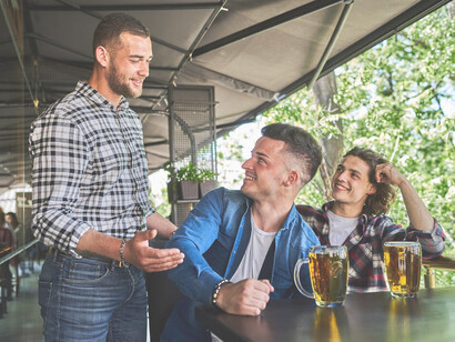 A group of three male friends having beers at a pub, engaging in lively conversation while enjoying their time together