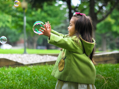 Bambina che gioca al parco con le bolle di sapone