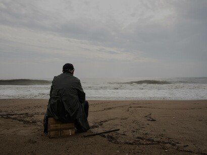 Homem observa o horizonte na praia