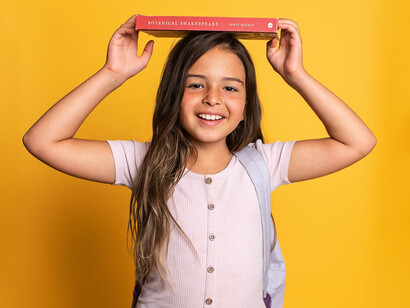 Criança brinca de equilibrar livro sobre a cabeça