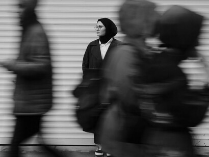 A woman standing still while the world moves around her in a blur, symbolising the practice of mindfulness in daily chaos