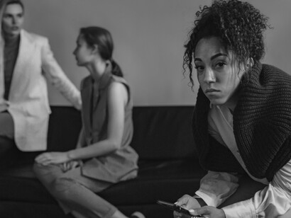 Enquanto duas mulheres conversam no sofá, outra permanece concentrada no celular, afastada da interação ao seu redor. A cena traduz o paradoxo das redes sociais: ferramentas criadas para conectar também podem enfraquecer as relações presenciais