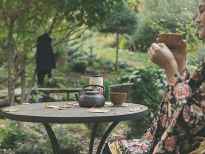 A woman in a garden sipping on tea