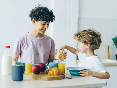 A mother and child at a table laden with healthy food; The gut microbiome can produce and modulate the production of neurotransmitters