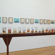 Valeska Soares, Not All Who Wander Are Aimless, 2014, Canvas, book pages, rum, nautical glasses, nautical paintings, reclaimed wood table, 11 canvas and book pages, 20.32 x 25.4 cm, 5 nautical paintings, 20.95 x 25.4 cm, 1 table, 415.5 x 110.5 x 30 cm, 34 nautical glasses, courtesy of Max Wigram Gallery and the artist