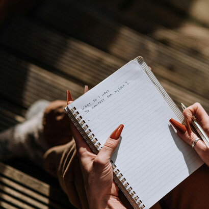 A woman in a brown blazer holds a cup of coffee in a moment of quiet reflection