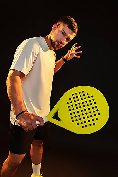 Competitive padel player preparing to return the ball during a fast-paced indoor matc