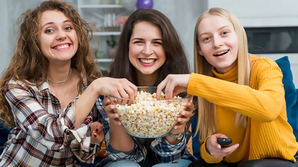 Enjoying quality time, friends gather to watch a TV series, indulging in popcorn snacks for a delightful viewing experience
