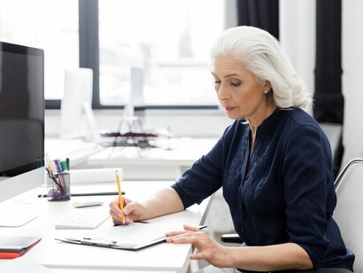 A senior businesswoman confidently working at her desk, representing the valuable role of older adults in the workforce