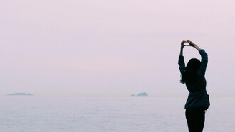 A woman in a peaceful setting is expressing her self-love to the world