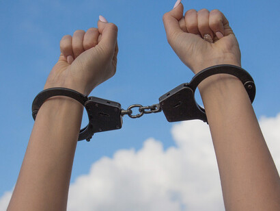 Under the vast sky, the image of female hands locked in handcuffs speaks volumes about the struggle for freedom and the fight against oppression