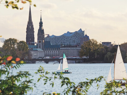 People enjoying a boat ride on the Alster in Hamburg, surrounded by city buildings in the daytime