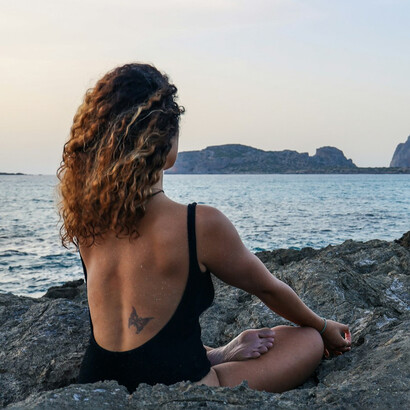 A woman sitting by the beach and indulging in the mindfulness brought by yoga 