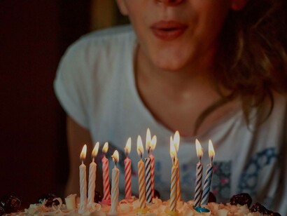 A woman enthusiastically blowing out her 13 candles as a milestone of entering teenagehood 