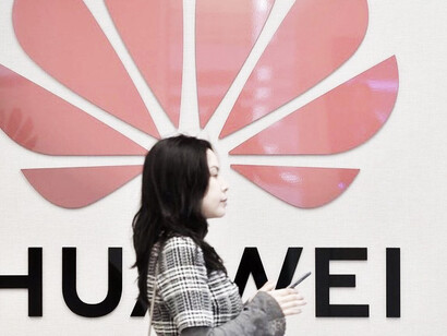 Una mujer pasa delante de un logo de Huawei