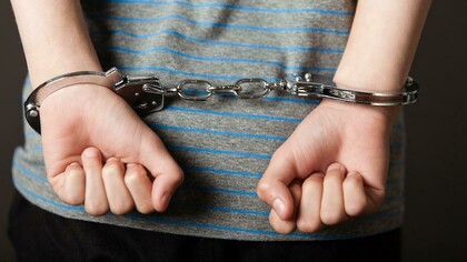 A young teenage boy being arrested for a committed crime