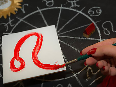 Female astrologer draws leo zodiac sign on white tile